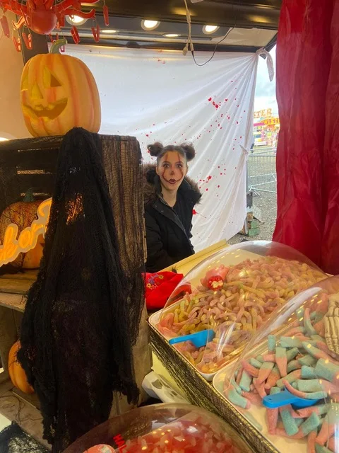 Girl wearing Halloween makeup beside the decorated S&B sweet stall